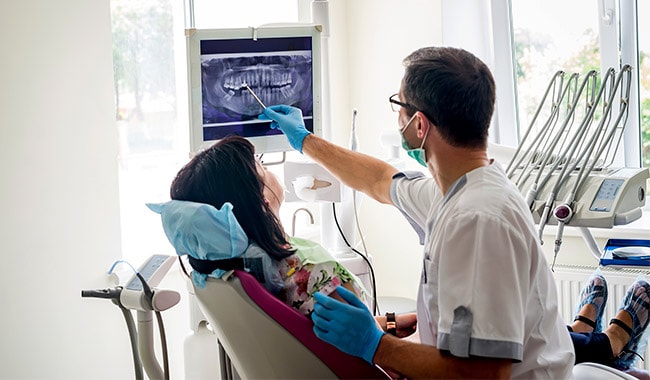 Dentist going over mouth x-rays with patient sitting in chair,