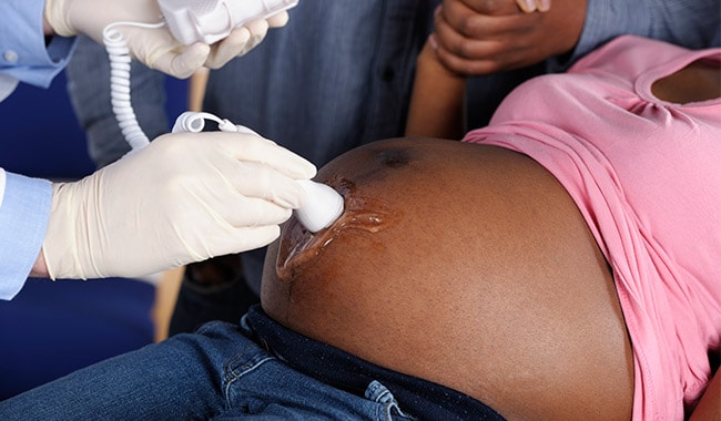 doctor checking pregnant patient's belly
