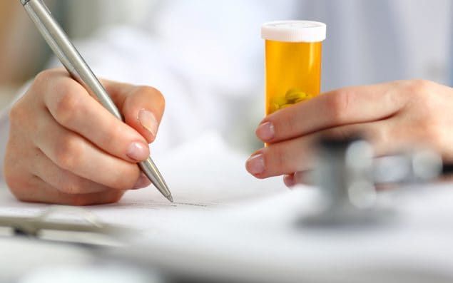 New York and Oklahoma Make it Easier for Persons with Behavioral Health Conditions to Access Non-Nicotine Cessation Medications - photo of a woman's hands holding a prescription bottle and writing notes.