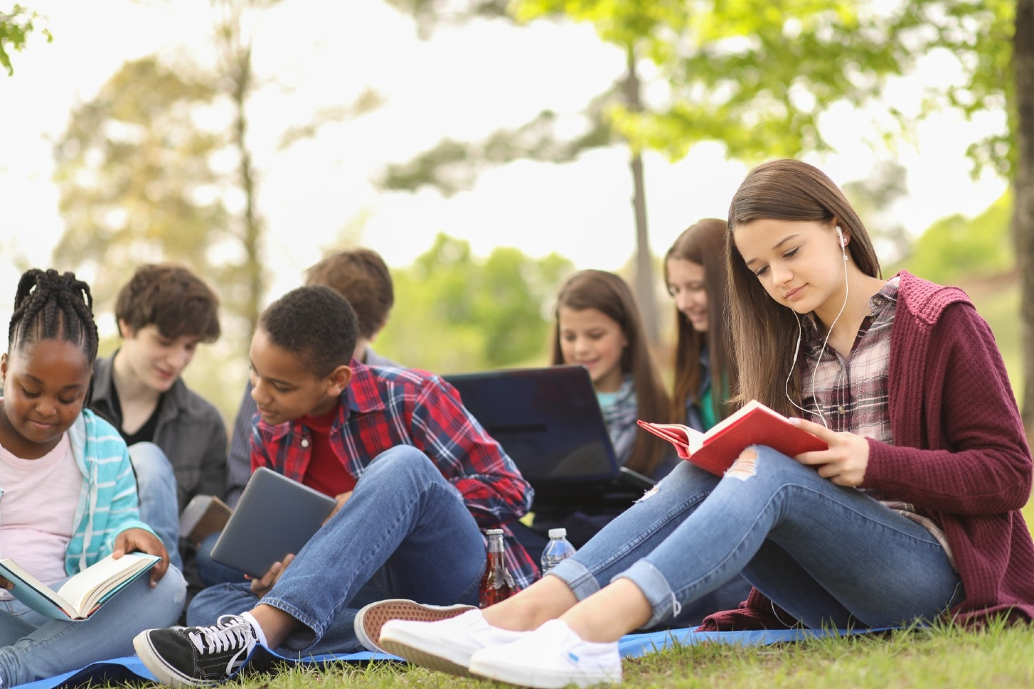 Grupo de jóvenes sentados afuera leyendo
