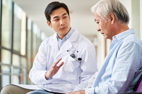 asian doctor talking to elderly man