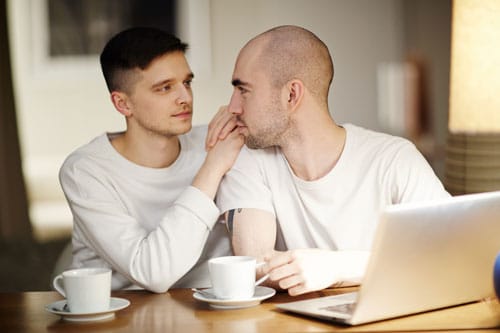 Guy couple at a table drinking coffee