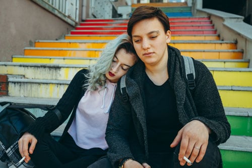Lesbian Couple sitting at the bottom of stairs with LGBT colors