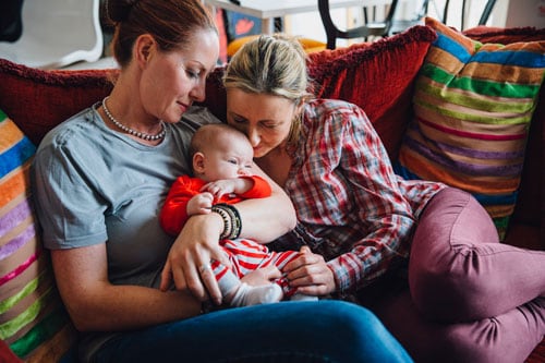 Lesbian couple sitting on couch with infant