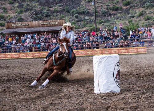 Photo of a woman riding her horse on a rodeo.