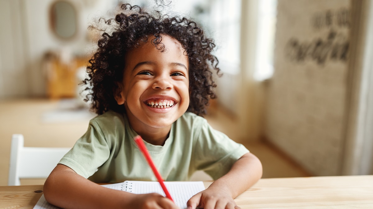 boy writing on notepad and smiling