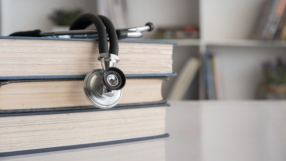A stethoscope rests on a stack of books.