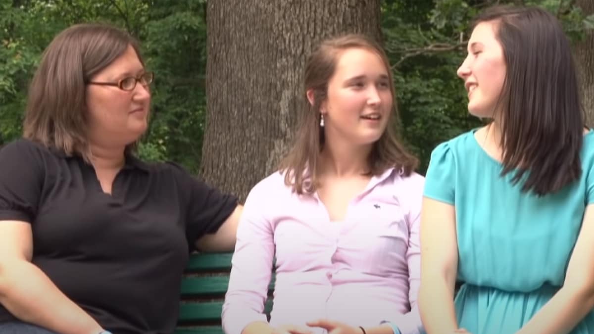 Three women sitting on park bench discussing TS