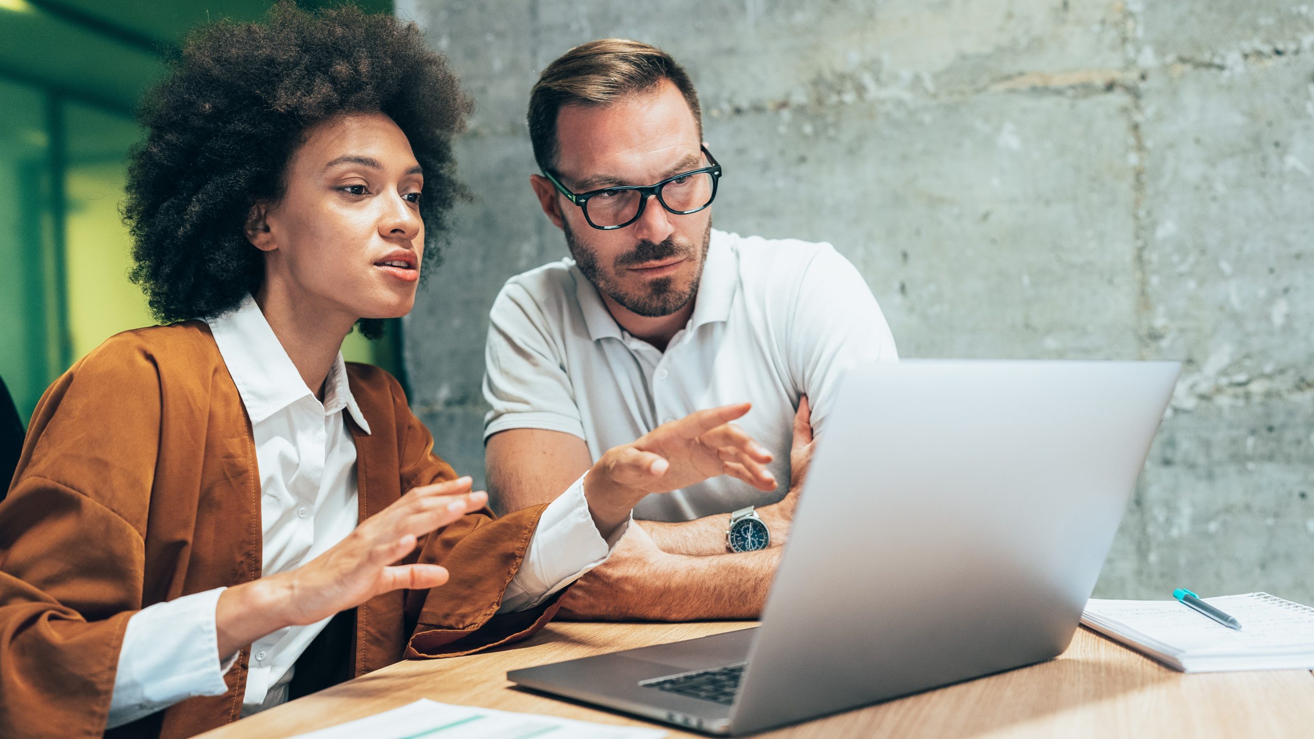 Two colleagues sharing a laptop while developing a new training.