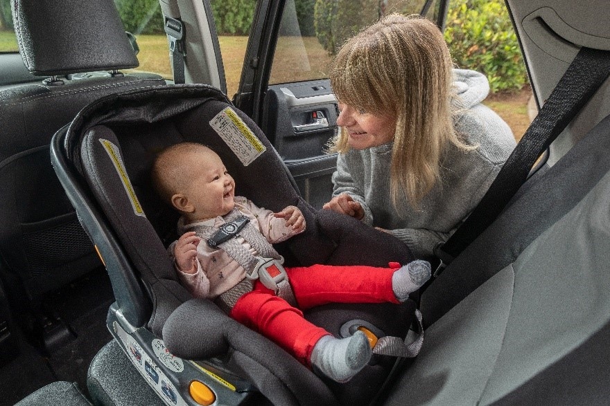 Woman next to baby strapped into rear-facing car seat