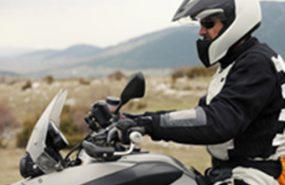 Man on white motorcycle with helmet and padding