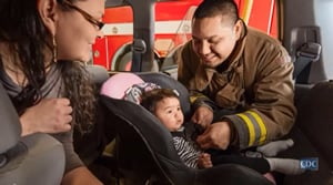 Fireman helping Native American mother with her child's car seat