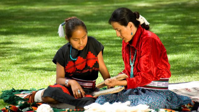 Native American adult and child sitting outside