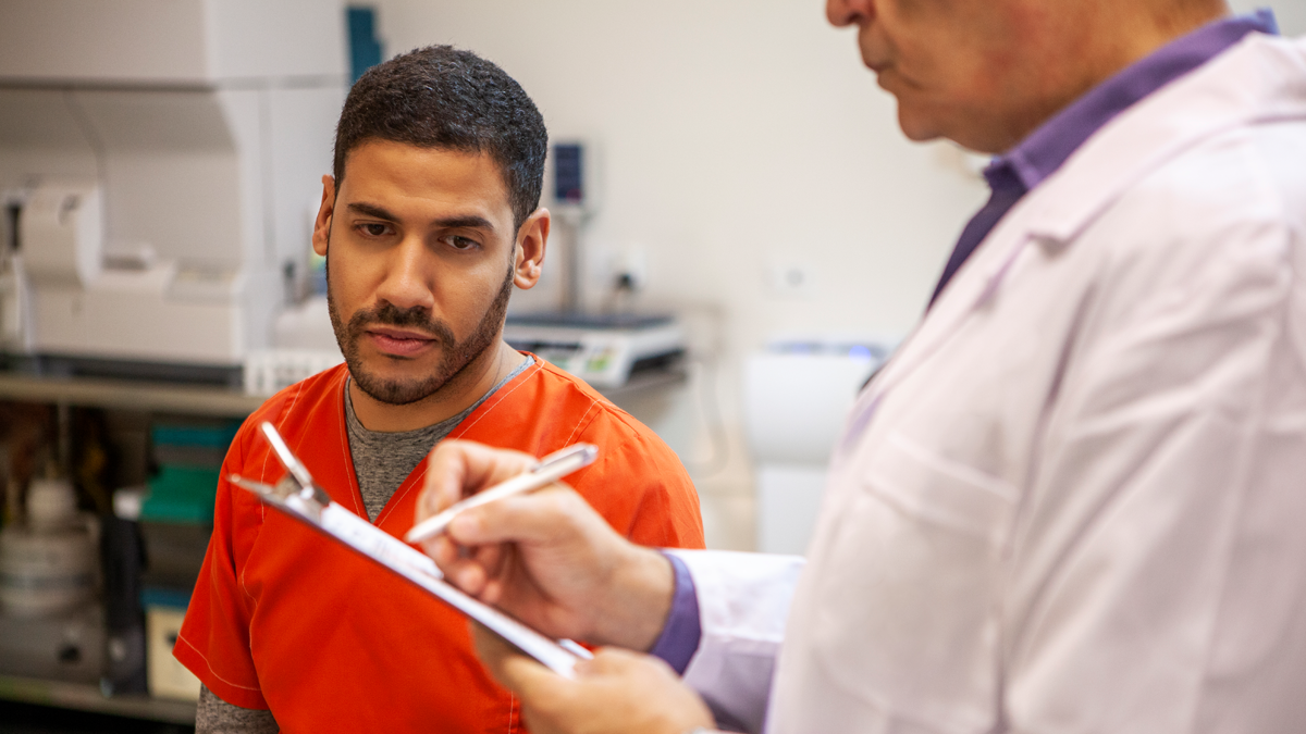 Man in correctional facility getting information from doctor