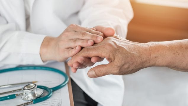Older adult patient holding a hand with doctor.