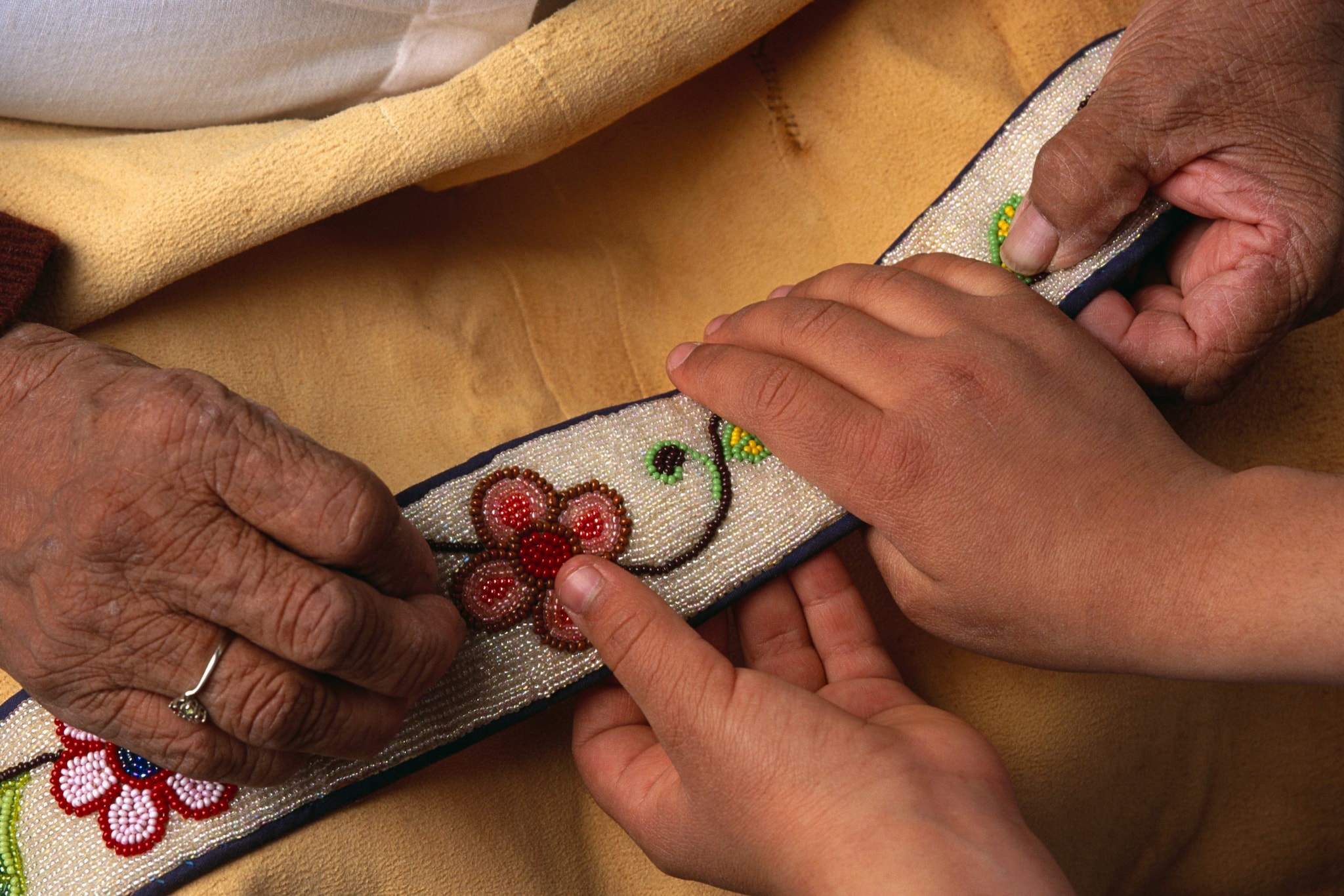 Intergenerational hands working together on beadwork