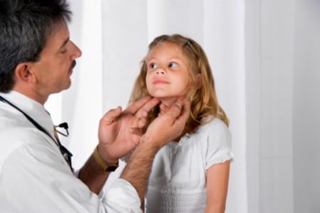 Male healthcare provider examining young girl's lymph nodes