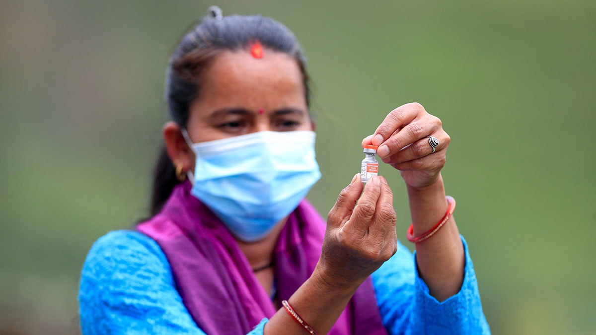 A health care worker holds a vial of vaccine.