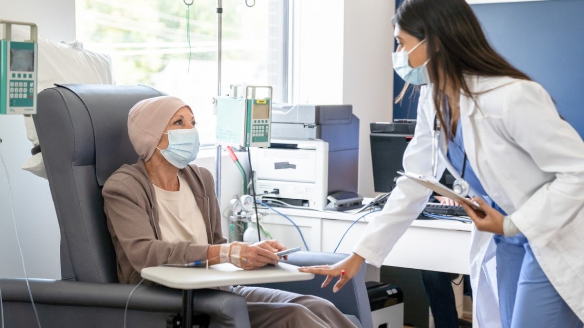 Photo of a nurse talking to a woman who is receiving chemotherapy