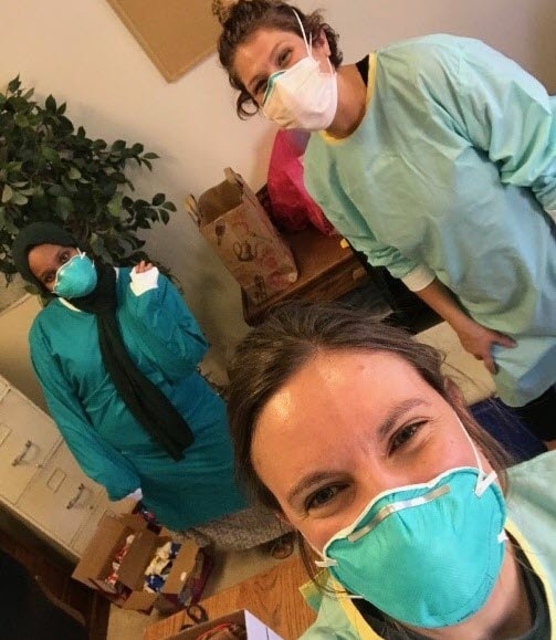 three women in an office in masks and medical scrubs