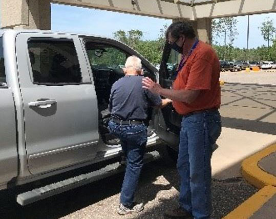 Volunteer helps senior into vehicle