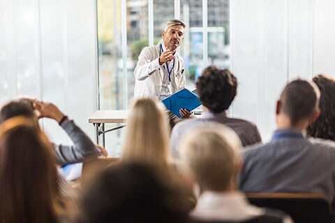 Doctor teaching in front of a classroom, students sitting