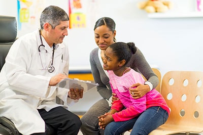 Male doctor talking with mother and female child
