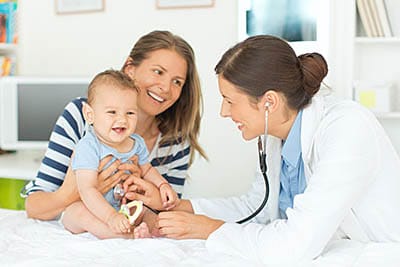 Female doctor examining baby with mother