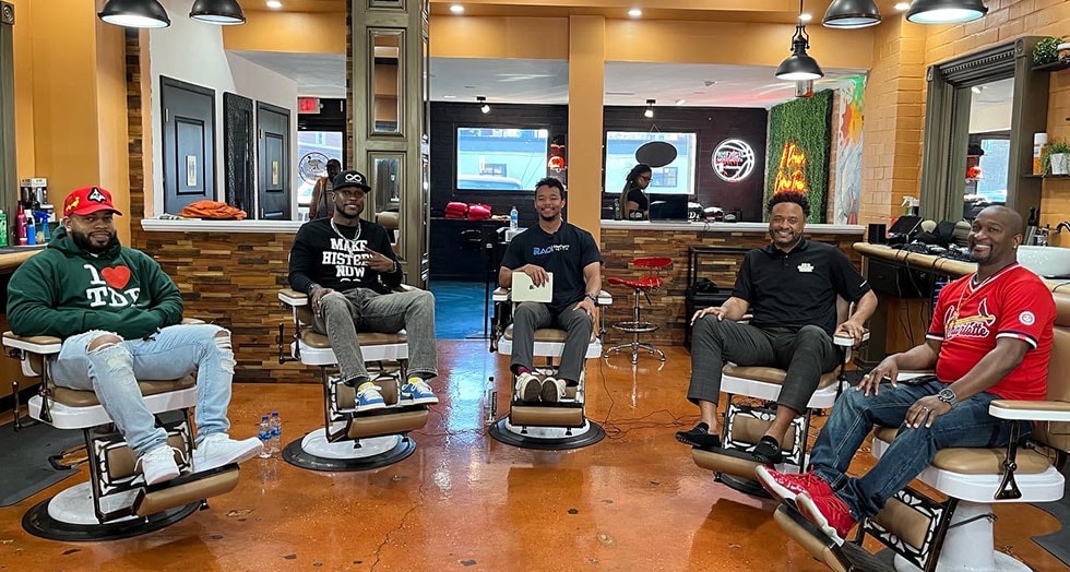 Group of five men sitting in barber chairs