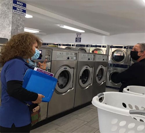 Worker approaches woman in a laundromat