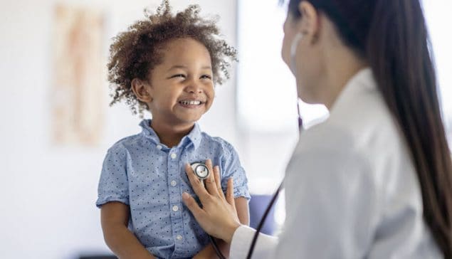 Médica asiaticoamericana atendiendo a un niño pequeño afroamericano.