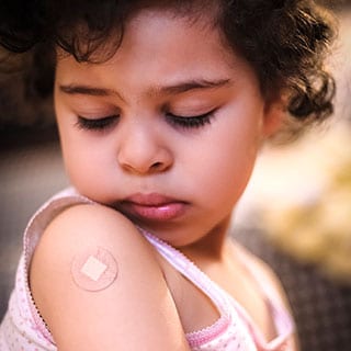 Little girl looking at a small bandage on her shoulder