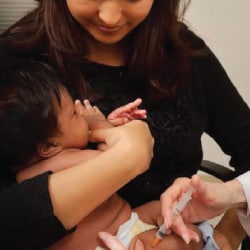 mother holding infant while getting vaccinated.