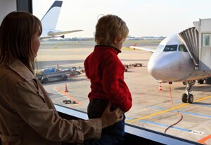 Mother and child looking at planes through an airport window