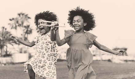 sisters laughing and running with toy airplane