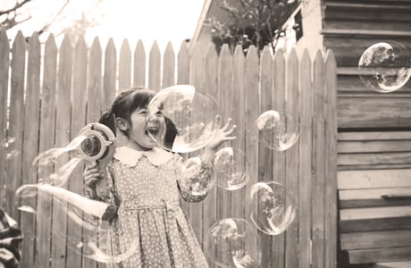 Niña jugando afuera con burbujas.