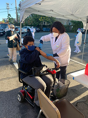 Person in a powered chair receiving vaccination in an outside clinic