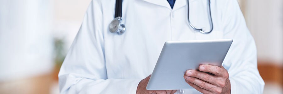 Doctor using a digital tablet in a hospital corridor.