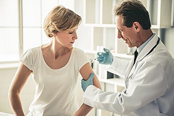 Male doctor immunizing a female patient