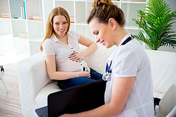 Female doctor showing pregnant woman information on a laptop