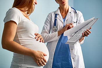 Pregnant woman and female doctor discussing medical chart