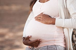 Mujer embarazada con una mano sobre el vientre.
