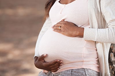 Mujer embarazada con las manos sobre el vientre.