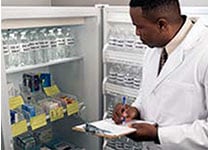 Male doctor taking inventory of drugs in refrigeration storage