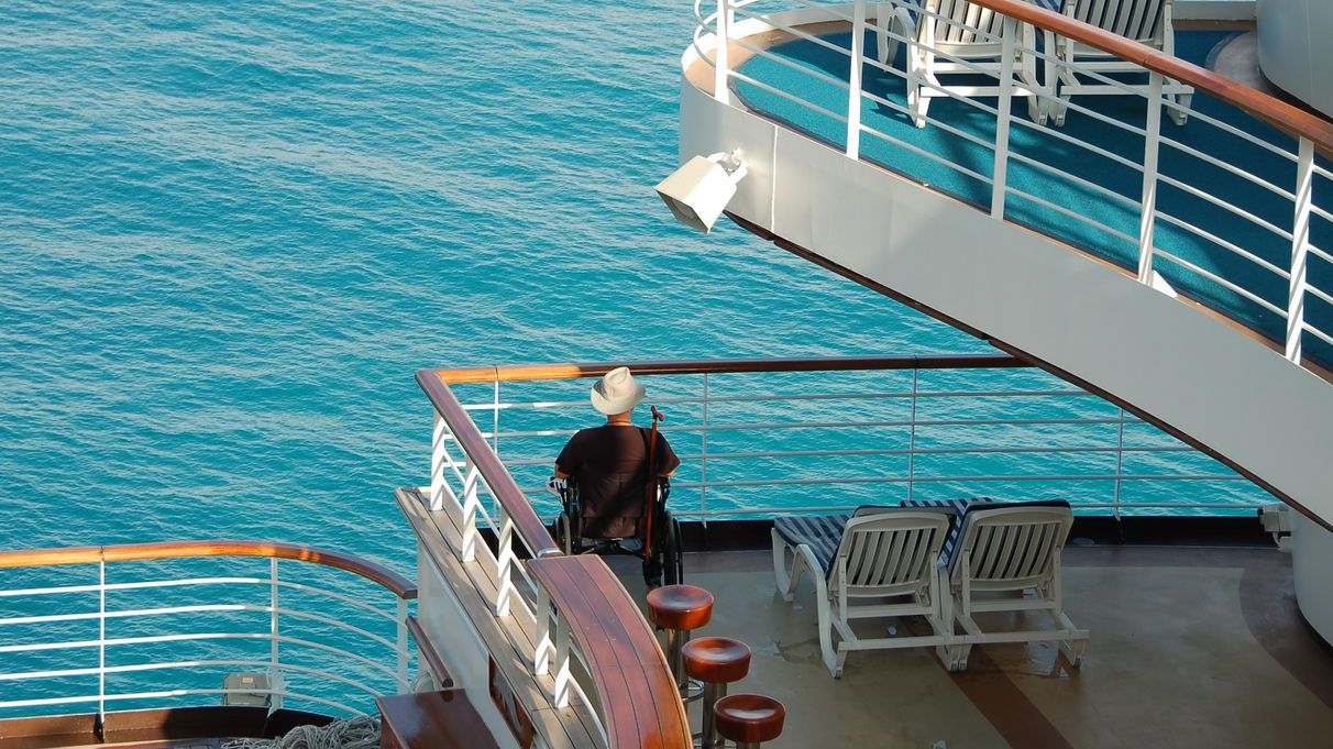 Boat decks at sea with a person in a wheelchair looking at the ocean.