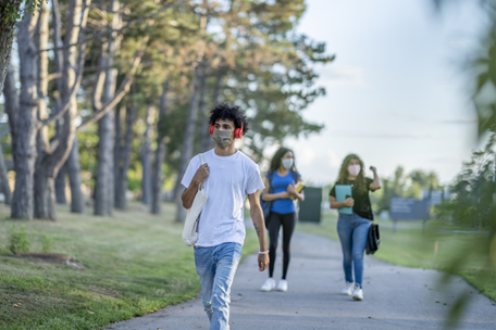 Image shows masked teens walking along a sidewalk