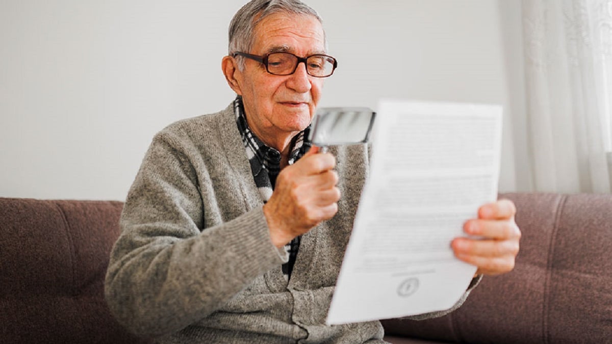 Older man reading with a magnifying glass.
