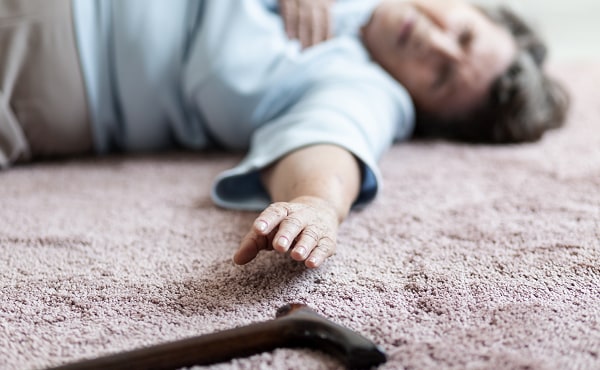 woman on floor reaching for cane