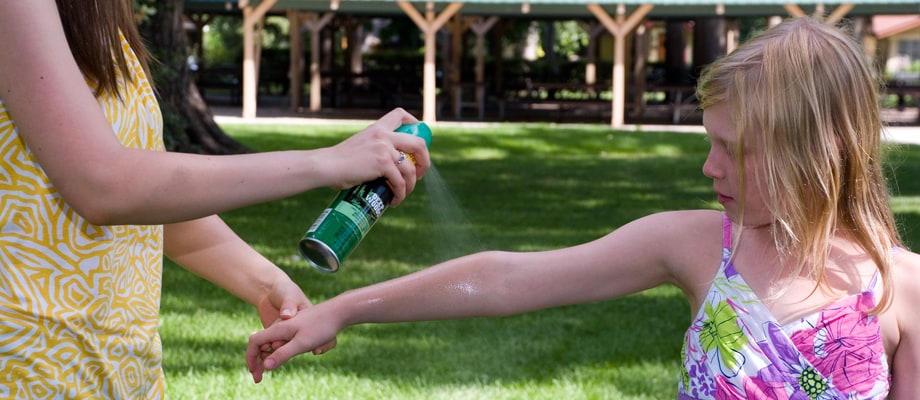 Spraying insect repellent over girl's arm