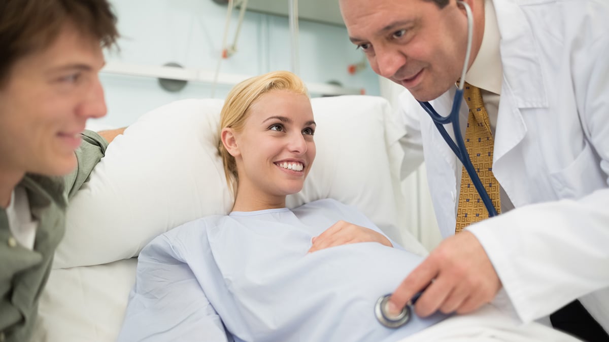 A doctor listening to a pregnant woman's belly with a stethoscope